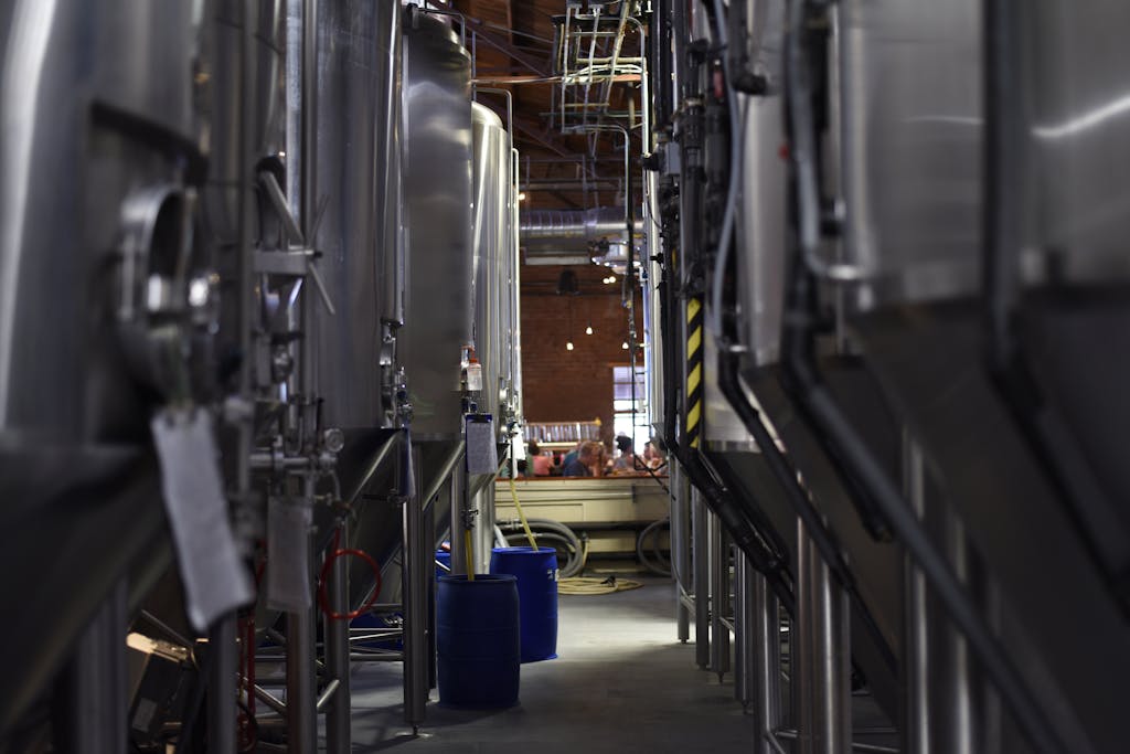 Inside view of a modern brewery with large stainless steel tanks and machinery for beer production.